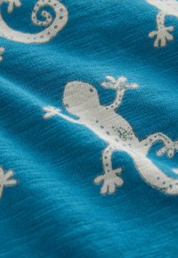 Tela azul con patrones de lagartos blancos que presentan extremidades detalladas, manchas y colas rizadas, creando un diseño texturizado y juguetón.