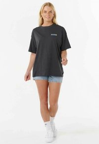 T-shirt en coton gris avec un col rond et des manches courtes, arborant un petit logo coloré sur la poitrine, assorti à un short en denim bleu.