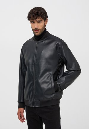 Giubbotto bomber in pelle nera con chiusura a zip frontale, colletto e polsini a coste, e tasche laterali, caratterizzato da una texture liscia e una vestibilità comoda.