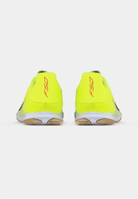 Φωτεινά κίτρινα αθλητικά παπούτσια με λεία υφή, διαθέτουν ελαφρύ σχεδιασμό, καουτσούκ σόλα και το λογότυπο "F50" σε κόκκινο χρώμα στη φτέρνα.