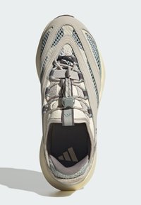 Bežové tenisky s textúrou sieťoviny a semišu, s šedým systémom šnurovania, polstrovaným jazykom a gumenou podrážkou. Logo Adidas na vnútorných vložkách.