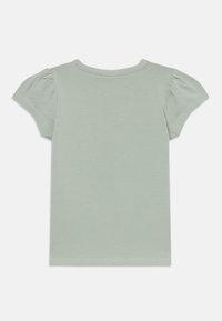 T-shirt verde claro com mangas bufantes curtas, decote redondo e uma textura suave. Apresenta um design simples e sólido, sem padrões.