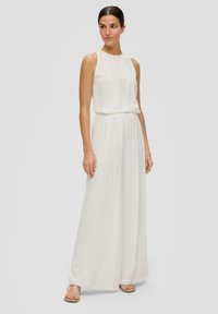 Witte mouwloze jumpsuit met een aansluitende lijfje en brede, vloeiende broekspijpen. Zachte stof met een gladde textuur. Gekenmerkt door minimale details.