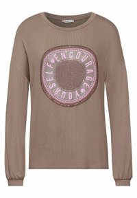 Braunes Langarmoberteil mit einem runden grafischen Design in Pink, auf dem "ERHEBE DICH SELBST" steht, und einem strukturierten Muster.