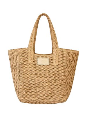 Bolsa tote tejida de paja natural tostada con dos asas y etiqueta rectangular de color blanco roto en el frente.