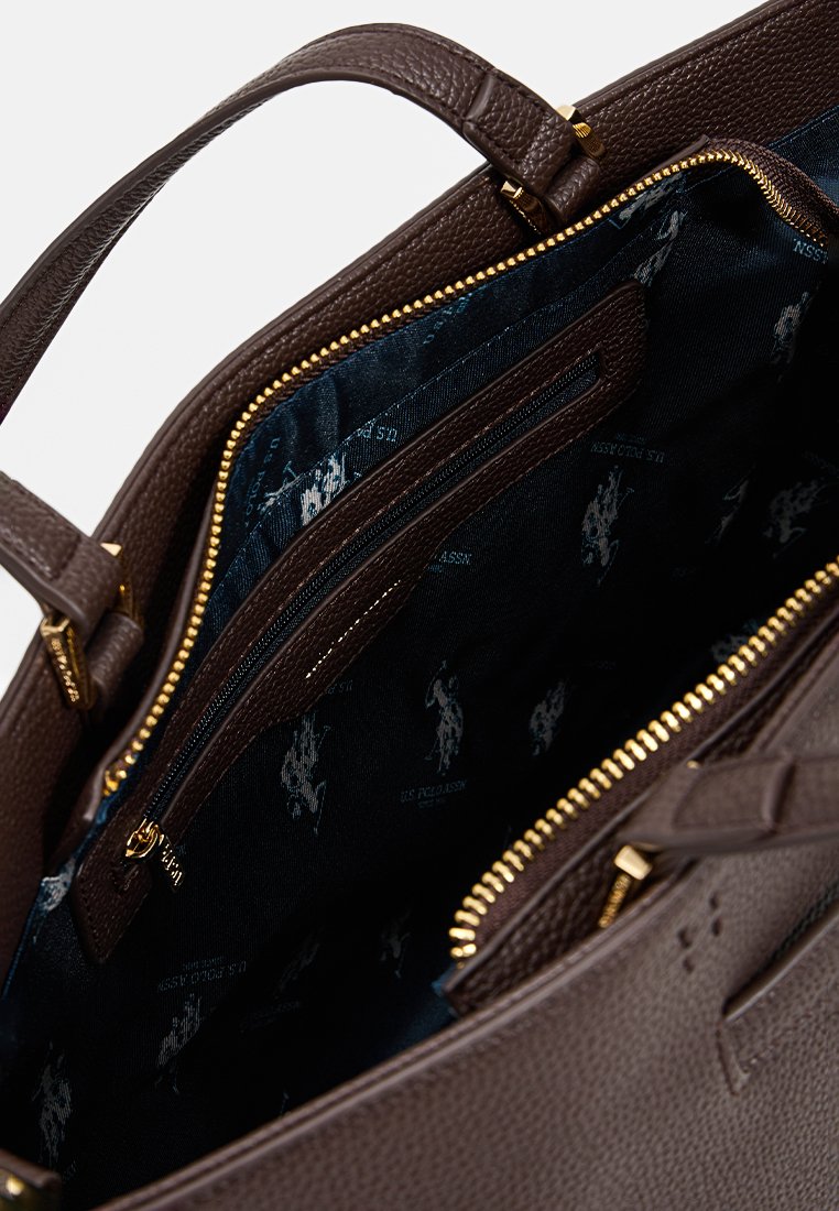 Bolso de mano de cuero marrón con un exterior texturizado, cremalleras doradas y un interior azul con un discreto patrón de logotipos y un bolsillo con cremallera.