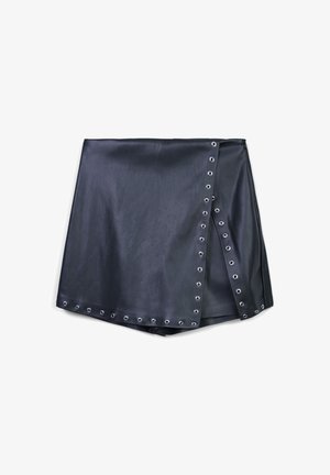 Mini gonna in finta pelle nera con rifiniture in occhielli metallici argentati lungo la sovrapposizione frontale e l'orlo inferiore, mostrata piatta su uno sfondo bianco.