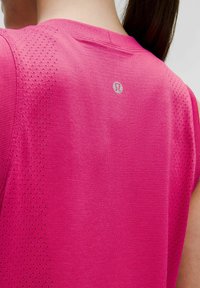 Ärmelloses Workout-Top in leuchtendem Pink mit strukturiertem Material, Mesh-Perforationen an den Schultern und einem kleinen Logo in der Nähe des Halsausschnitts.