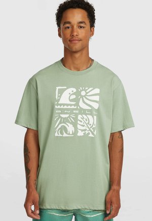 Svetlozelené bavlnené tričko s bielou potlačou blokových tvarov, vrátane vlny a listov; voľný strih, krátke rukávy.