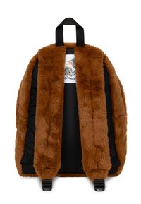 Zaino in pelliccia artificiale marrone con una texture morbida, interno imbottito nero, maniglia superiore e spallacci regolabili. Include un'etichetta con una grafica.