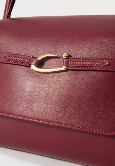 Burgundin nahkalaukku, jossa on kultasävyinen kiinnitys, yksityiskohtainen ompelu ja jämäkkä suorakulmainen muoto.