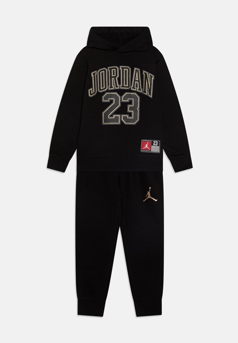Completo con felpa nera con cappuccio e pantaloni della tuta, che presenta la scritta "JORDAN" e il numero "23" in lettering dorato. Include un logo Jumpman dorato sui pantaloni.