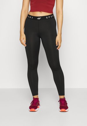 Leggings sportivi neri con vita alta e testo "SPORT" in bianco. Abbinati a scarpe rosse e un crop top abbinato.