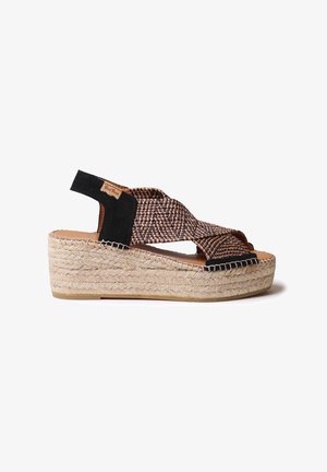 Sandal sa klinom s pletenim gornjim dijelom u crnoj i smeđoj boji, platformom od espadrile s užetom i glatkim kožnim detaljima. Dizajn s otvorenom petom.