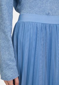 Gonna plissettata azzurro chiaro con una ampia cintura elastica, realizzata in un tessuto morbido, con un top integrato in un design a maglia testurizzata.