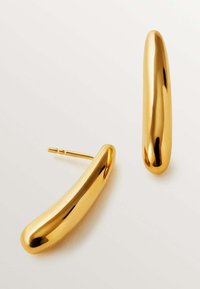Pendientes de metal tono dorado con un diseño estilizado y alargado, y una textura suave. Cuentan con un cierre de tipo poste para un uso seguro.