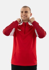 Pullover sportivo rosso con zip a quarto di giro, dettagli bianchi sulle spalle e tasca a marsupio. Presenta un logo sul petto e un tessuto morbido e texture.