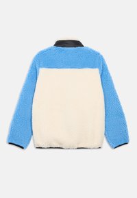 Jaqueta de fleece de mangas longas com mangas e painel superior traseiro em azul claro, painel traseiro médio em creme, e gola e orla em preto.