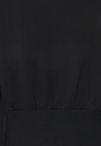 Czarna bluza z miękkim, teksturowanym wykończeniem, z marszczonym pasem i luźnym krojem. Brak widocznych wzorów lub akcentów.