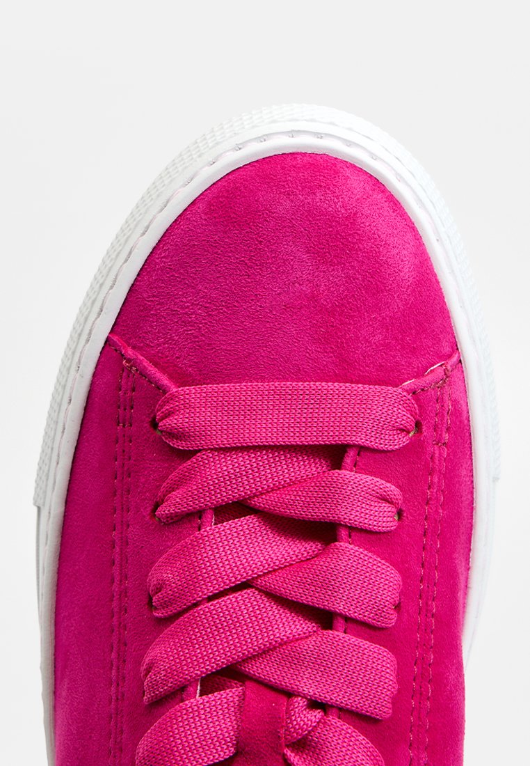 Helle pinke Wildleder-Sneaker mit passenden Schnürsenkeln und weißer Gummisohle, von oben betrachtet, mit Fokus auf der Zehen- und Schnürbereich.