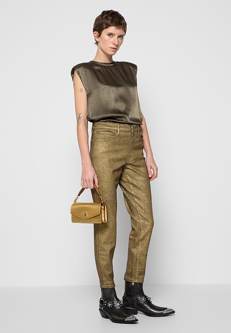 Oliwiany satynowy top z krótkimi rękawami, złote metaliczne spodnie, czarne botki za kostkę z srebrnymi akcentami i mała złota torebka.