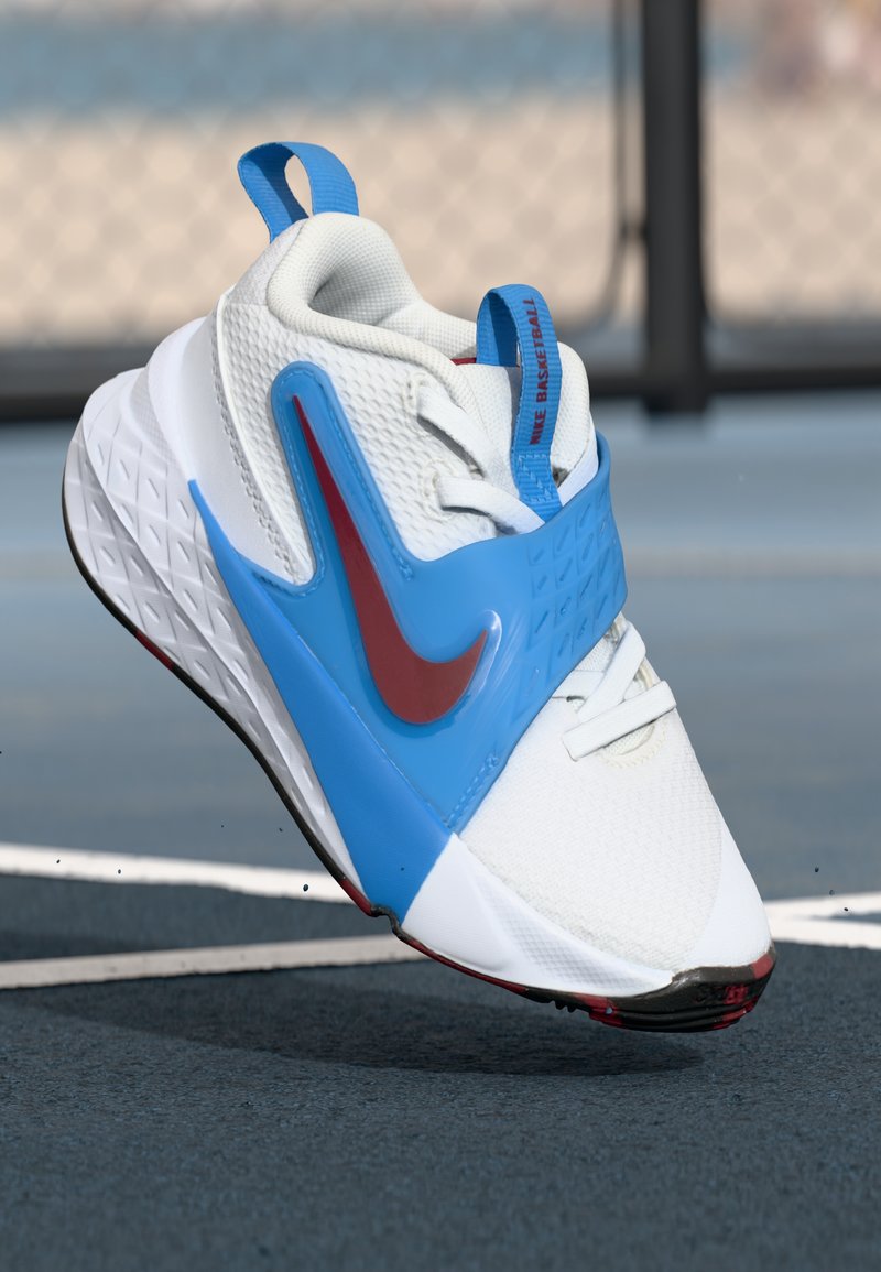 Bílé a modré basketbalové tenisky Nike mají texturovaný svršek, výrazné červené akcenty a flexibilní design. Gumová podrážka s vzorovaným gripem.