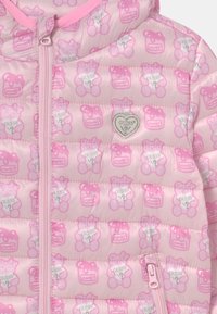 Chaqueta acolchada rosa con patrones de osos y tarros de miel, logo de corazón plateado y cremallera con tirador a juego. Textura suave, diseño acolchado.