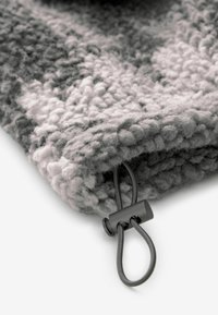 Tkanina o teksturze w odcieniach szarości z pluszowym, pętelkowym wzorem. Posiada czarny zamek na zatrzask dla pewnego zapięcia.