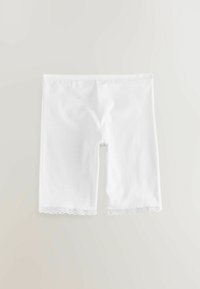 Fehér pamut kerékpáros rövidnadrág sima textúrával, a szegélyén hullámos csipkedíszítéssel. Combközépig érő hosszúságú és rugalmas kialakítású.