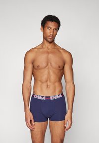Marineblaue Boxer mit einem elastischen Bund in Weiß und Rot, der mit "DIM" bedruckt ist. Der Stoff ist glatt, enganliegend und leicht.