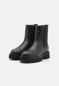 Sorte ankelstøvler i svart lær med elastiske sidestykker, en kraftig såle og en glattere overflate, designet for holdbarhet og komfort.