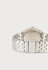 Silver stainless steel watch with a link bracelet, square case, and round face. Features a smooth finish and visible clasp.