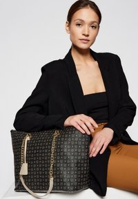 Borsa tote nera con motivo logo dorato, dettaglio a catena e tracolla crema. Materiale strutturato e design spazioso.