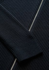 Pull en laine bleu marine avec texture côtelée, doté d'une fermeture éclair argentée sur le devant et de manches fuselées pour un look ajusté.