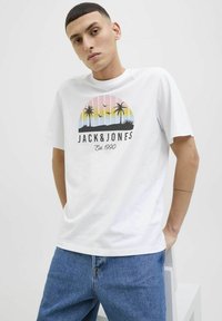 Bílý bavlněný tričko s grafickým potiskem palm a barevného západu slunce, obsahující text "JACK & JONES" a "Est. 1990". Volný střih.