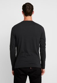 Langärmliges schwarzes T-Shirt aus Baumwolle mit Rundhalskragen und geradem Saum. Die Rückansicht zeigt die glatte Textur und das schlichte Design.