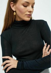 Melna garām piedurknēm turtlenecks ar vieglu, pieguļošu dizainu un ribota tekstūra. Komplektēts ar zeltītām asaru formas auskaru. 
