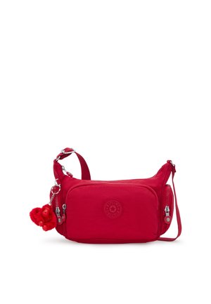 Sac bandoulière en nylon rouge avec poches zippées avant et latérales, bandoulière ajustable et porte-clés rouge duveteux attaché.