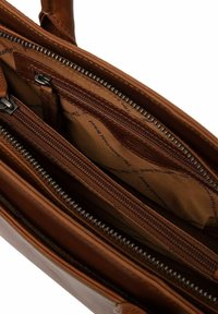 Interieur van een bruine leren handtas met meerdere compartimenten, waaronder ritszakken en een stoffen voering met een subtiel logopatroon.