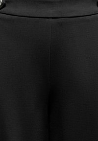 Czarne spodnie z tkaniny o teksturowanym splocie, z gładkim paskiem i ozdobnymi guzikami z przodu do zapinania.