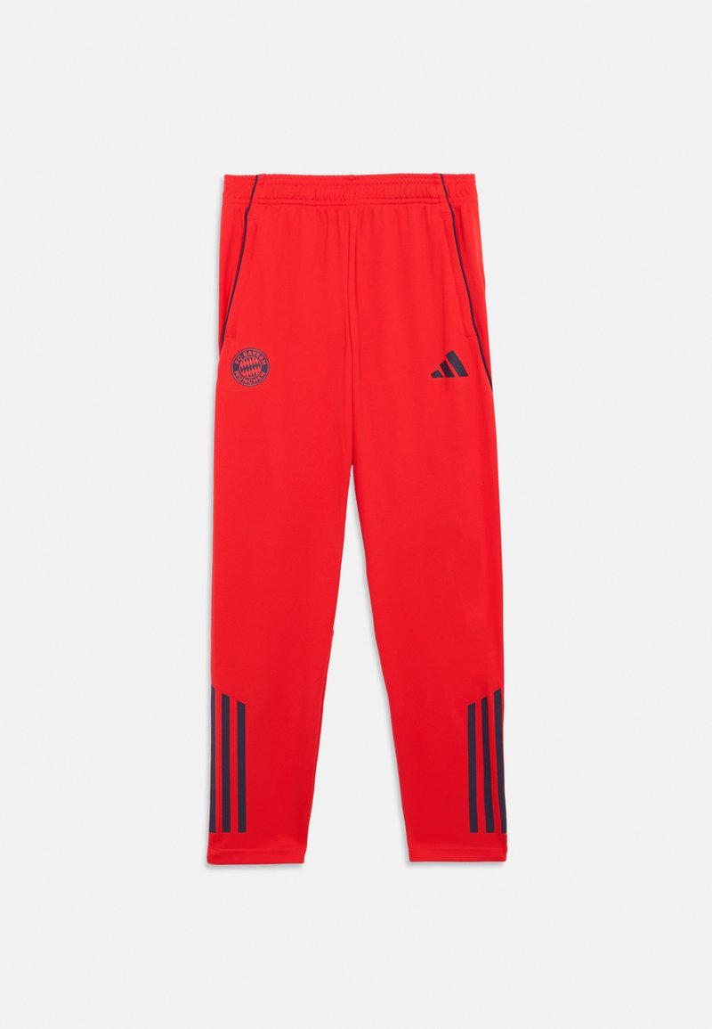 Κόκκινες αθλητικές παντελόνες με ελαστική μέση, πλαϊνές τσέπες, μπλε διακοσμητικές ρίγες στο τελείωμα και λογότυπο της Bayern Munich στο μηρό.
