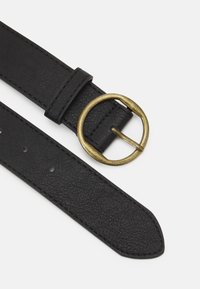 Ceinture en cuir noir avec une finition texturée, dotée d'une boucle ronde en laiton et de plusieurs trous d'ajustement sur toute sa longueur.