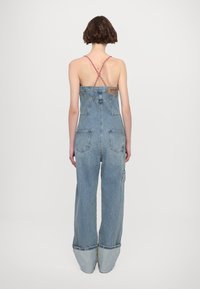Denim salopete z ohlapnim krojem, svetlo modre barve, z igračo čez hrbet, dvema zadnjima žepoma in zavitimi manšetami.