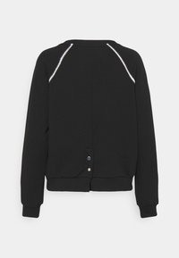 Sudadera negra con cuello redondo, puños acanalados y costuras en contraste a lo largo de las costuras raglán. Detalle de botón en el dobladillo trasero.