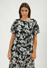 Schwarzes Blumenkleid mit einem weißen Blumenmuster. Entworfen mit kurzen, transparenten Ärmeln und einer taillierten Taille, die mit einem Kordelzug betont wird.