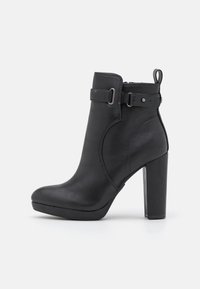 Bottine en cuir noir avec un talon bloc haut, dotée d'une fermeture éclair latérale, d'un accent de boucle et d'une texture lisse.