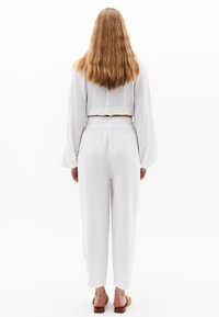 Witte, loszittende, cropped blouse met lange mouwen, gecombineerd met hoge taille, rechte pijpen broek, beide gemaakt van lichtgewicht stof.