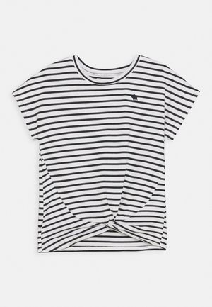 Biała koszula z krótkim rękawem z czarnymi poziomymi paskami i małym czarnym logo zwierzęcia na lewej piersi, z przodem z detalem skrętu.