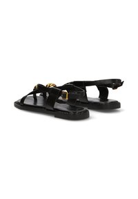 Sandalias planas negras con tiras entrelazadas, hebilla dorada y acentos decorativos dorados sobre un fondo blanco.