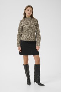 Beige und dunkelbrauner langärmeliger Leopardenprint-Oberteil, kombiniert mit einem schwarzen Denim-Rock und knielangen schwarzen Stilettos.